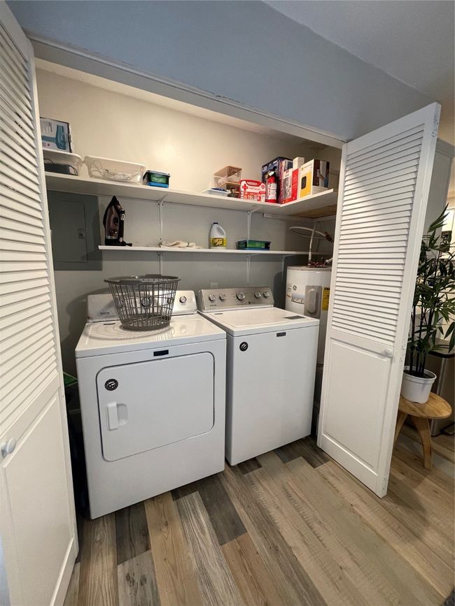 Laundry room featuring light wood-type flooring, washing machine and clothes dryer, and electric panel | Image 8