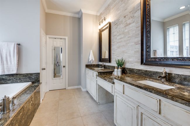 Bathroom featuring double vanity, a jetted tub, crown molding, large format tile flooring and a beautiful backsplash | Image 30