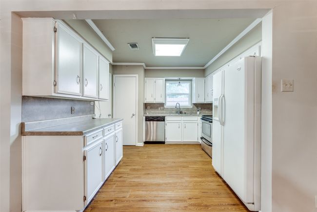 Kitchen featuring stainless steel appliances, a sink, crown molding, light wood-style flooring, and decorative backsplash | Image 8