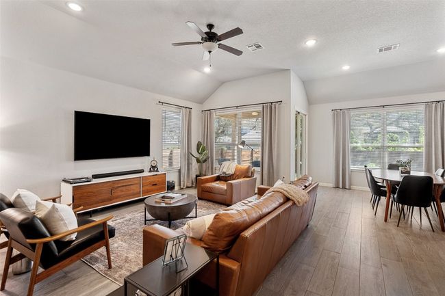 Living area featuring lofted ceiling, plenty of natural light, light wood-style floors, ceiling fan, and recessed lighting | Image 6