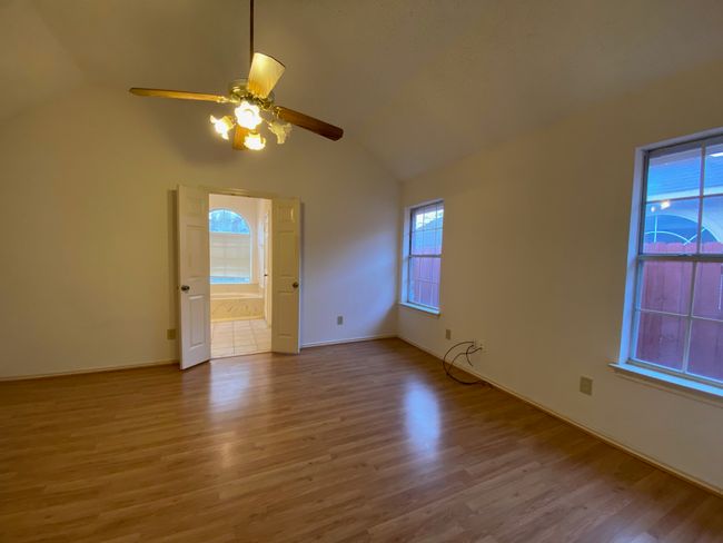 Empty room with lofted ceiling, healthy amount of natural light, wood finished floors, and ceiling fan | Image 16