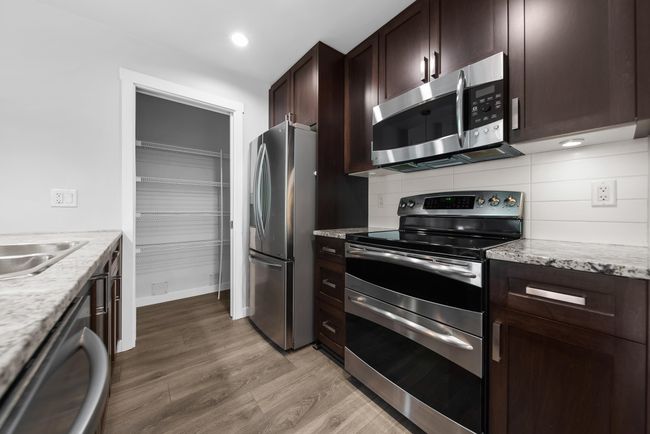 Kitchen with stainless steel appliances, light wood-type flooring, dark brown cabinetry, backsplash, and recessed lighting | Image 28