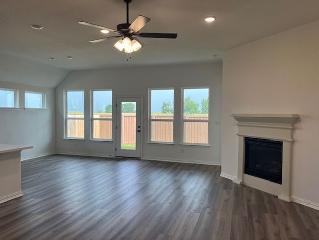 Unfurnished living room featuring plenty of natural light, dark wood-type flooring, a fireplace, baseboards, and recessed lighting | Image 6