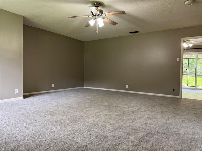 Spare room featuring a ceiling fan, carpet floors, a smoke detector, and a textured ceiling | Image 5
