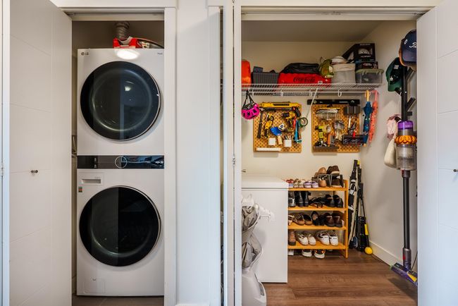 Laundry area with stacked washer / drying machine and wood finished floors | Image 20