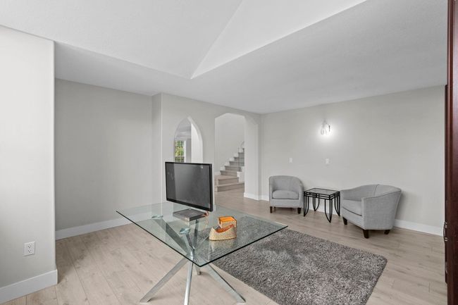 Living area featuring arched walkways, vaulted ceiling, light wood-style floors, and stairs | Image 17