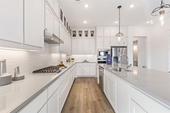 Kitchen with hanging light fixtures, white cabinets, stainless steel appliances, sink, and light hardwood / wood-style floors | Image 27