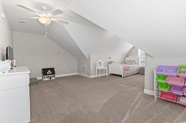 Bedroom featuring carpet flooring, a ceiling fan, baseboards, vaulted ceiling, and visible vents | Image 30