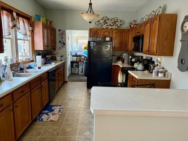 Kitchen featuring light countertops, a sink, plenty of natural light, and black appliances | Image 18