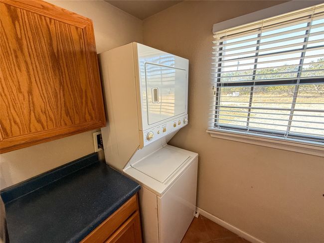 Laundry room with stacked washer and dryer, cabinet space, baseboards, and tile patterned flooring | Image 16