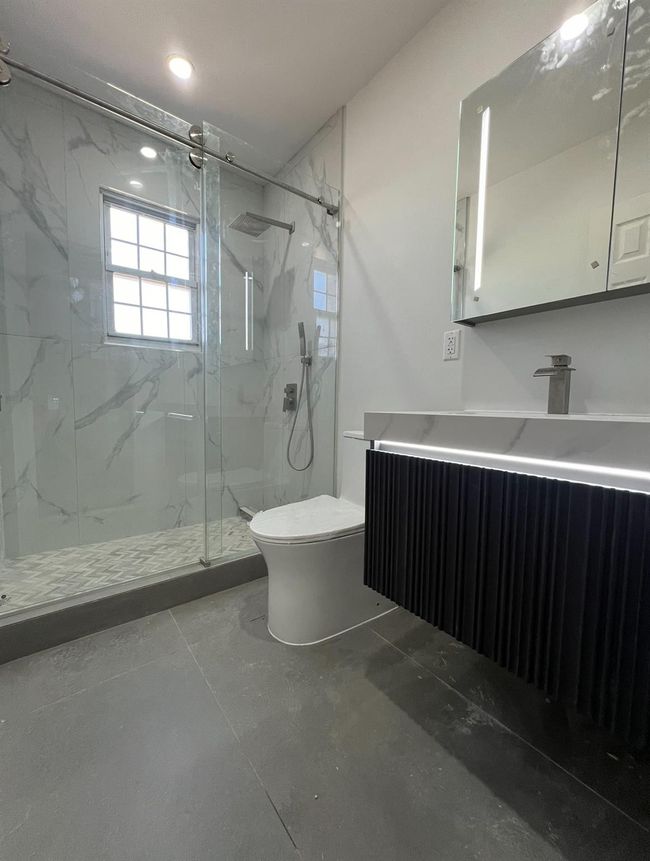 Full bath with a marble finish shower, toilet, recessed lighting, vanity, and radiator | Image 8