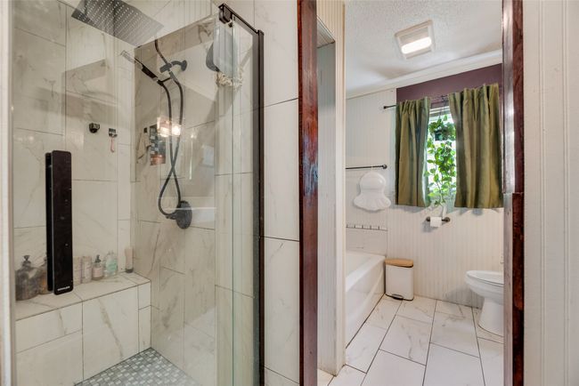 Full bath featuring ornamental molding, marble finish floor, toilet, a textured ceiling, and a stall shower | Image 19