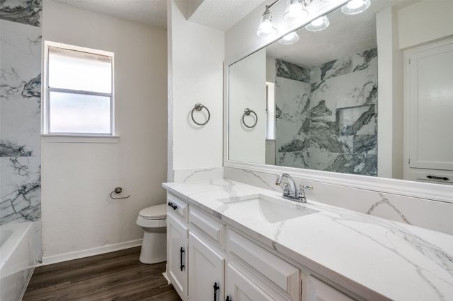 Full bathroom featuring vanity, a tub to relax in, wood finished floors, a shower, and a textured ceiling | Image 20