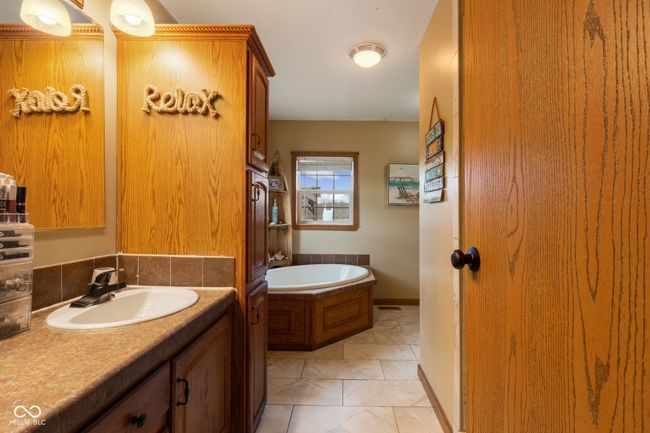 bathroom with a bath, marble finish floor, vanity, and baseboards | Image 39