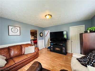 Living room featuring a stone fireplace, a textured ceiling, and light wood-type flooring | Image 3