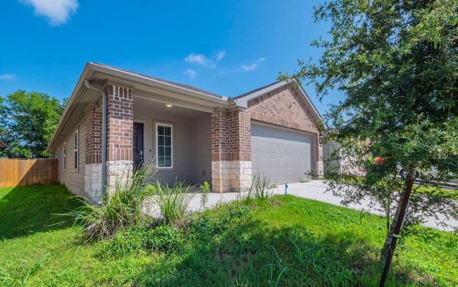 View of property exterior with brick siding, an attached garage, stone siding, and driveway | Image 22