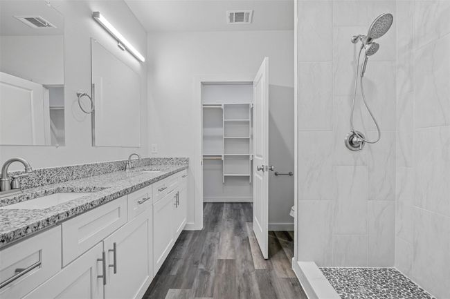 Bathroom featuring double vanity, wood finished floors, tiled shower, and a spacious closet | Image 11