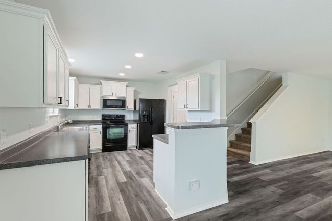 Kitchen featuring black appliances, Grey wood-style vinyl floors, a sink, dark countertops, and recessed lighting | Image 14