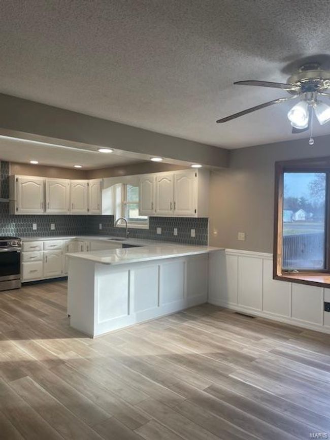 Kitchen featuring white cabinetry, sink, light hardwood / wood-style flooring, kitchen peninsula, and stainless steel electric range | Image 13