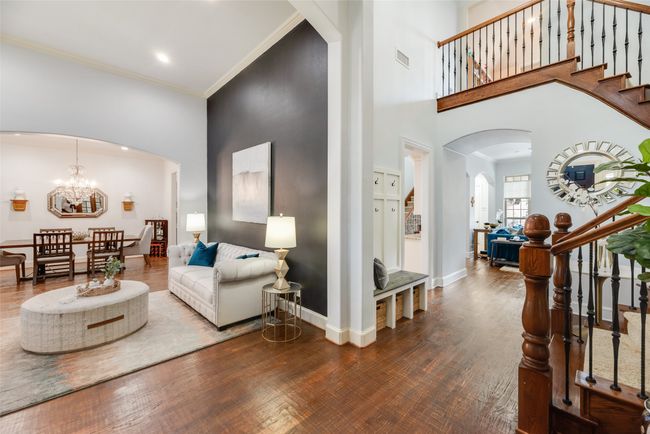 Living room with stairs, a high ceiling, arched walkways, wood finished floors, and crown molding | Image 26