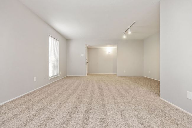 Empty room with baseboards, track lighting, and light colored carpet | Image 5