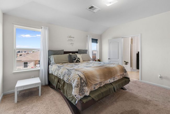 Bedroom featuring baseboards, lofted ceiling, visible vents, and light carpet | Image 26