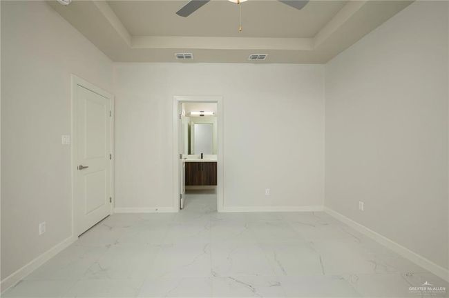 Empty room featuring a tray ceiling, light marble finish flooring, baseboards, and ceiling fan | Image 17
