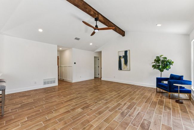 Exposed beams and expansive windows flood the living area with natural light. | Image 7
