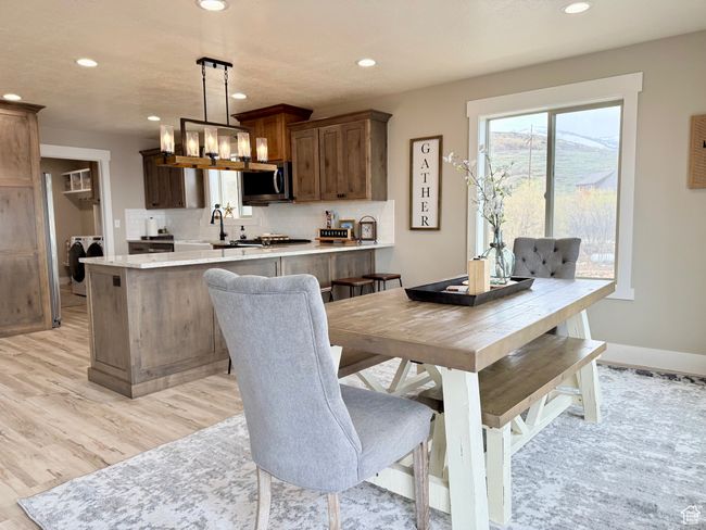 Dining space with washer / dryer, baseboards, light wood-style floors, recessed lighting, and a notable chandelier | Image 25