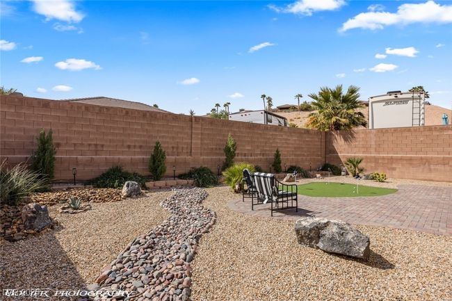 Fenced backyard with an area to practice putting and a patio area | Image 51