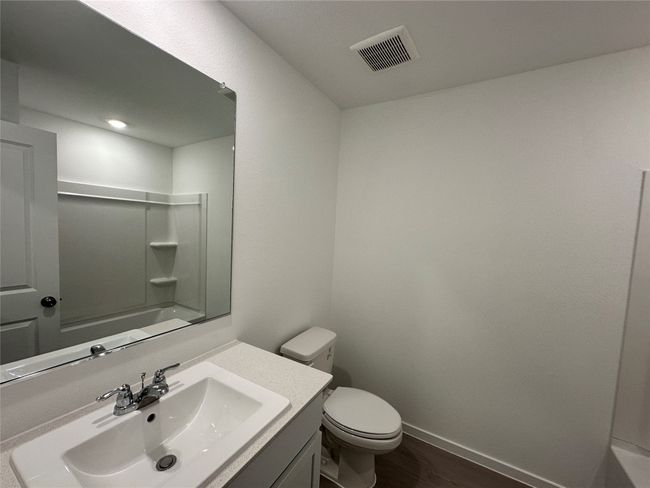 Bathroom featuring toilet, wood finished floors, vanity, baseboards, and bathing tub / shower combination | Image 11
