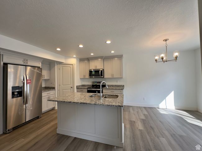 Kitchen LVP floors, appliances with stainless steel finishes, decorative light fixtures, and sink | Image 4