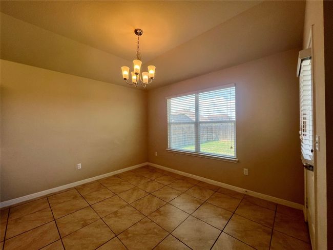 Breakfast area featuring light tile patterned flooring, a chandelier, baseboards, and lofted ceiling | Image 26