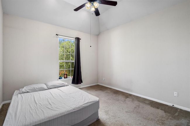 Bedroom with carpet, baseboards, vaulted ceiling, and a ceiling fan | Image 25