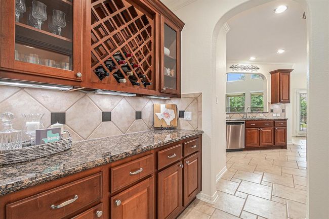 A butler's pantry features additional storage space, glass front cabinets and wine storage! Perched between the formal dining room and kitchen, this spot makes perfect sense! | Image 14