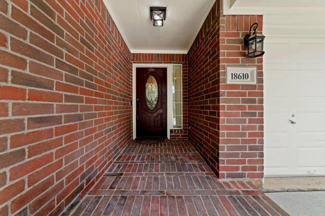 Stepping onto the covered patio, welcomed by a crafted fiberglass door and adorned of elegant glass surrounded in timeless brick and mortar — the cozy feeling of home as you arrive home. | Image 5
