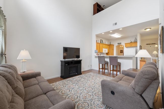 Living room with wood finished floors, baseboards, arched walkways, and a towering ceiling | Image 8