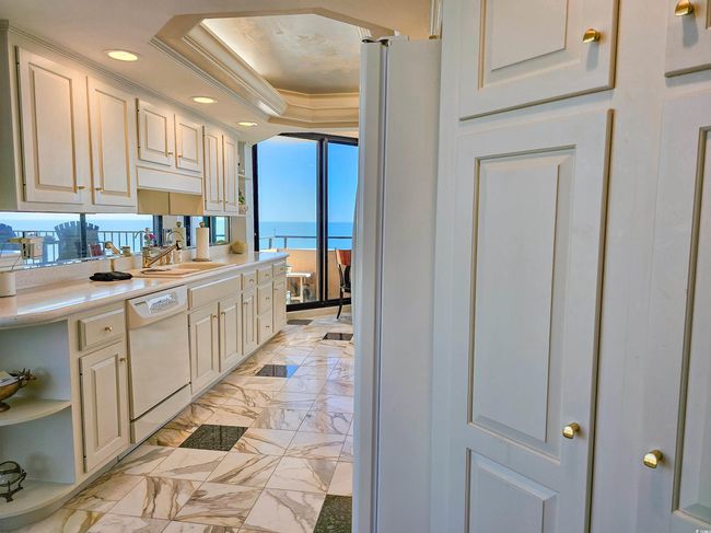 Kitchen with a sink, white appliances, light countertops, recessed lighting, and a tray ceiling | Image 10