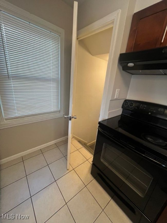 Kitchen featuring black electric range, dark brown cabinets, and light tile floors | Image 24