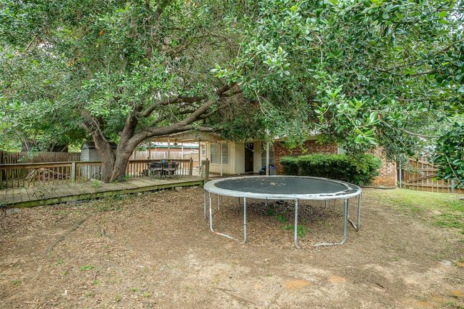 Fenced backyard featuring a trampoline and a wooden deck | Image 31