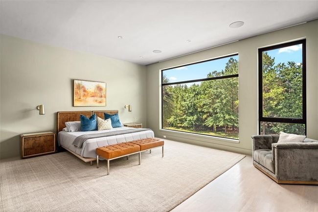 Framed by oversized picture windows, the serene primary suite offers uninterrupted treetop views that create a calming, retreat-like atmosphere. Soft green walls by Farrow & Ball, pale hardwood floors, and minimalist lighting elevate the space with understated luxury, while the expansive layout allows room to relax and unwind in total privacy. | Image 17