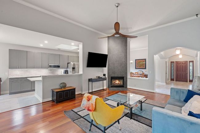 Living area with light wood-style flooring, arched walkways, and ornamental molding | Image 7
