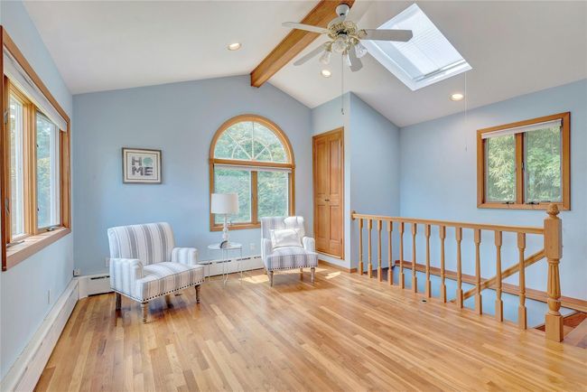Sitting room/den with a skylight, wood finished floors, a ceiling fan, and an upstairs landing | Image 11