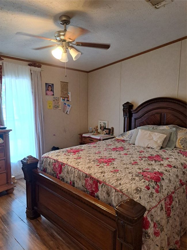 Bedroom featuring multiple windows, light wood finished floors, crown molding, ceiling fan, and a textured ceiling | Image 12