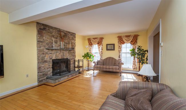 Living room with hardwood / wood-style floors, a baseboard heating unit, baseboards, and a stone fireplace | Image 18