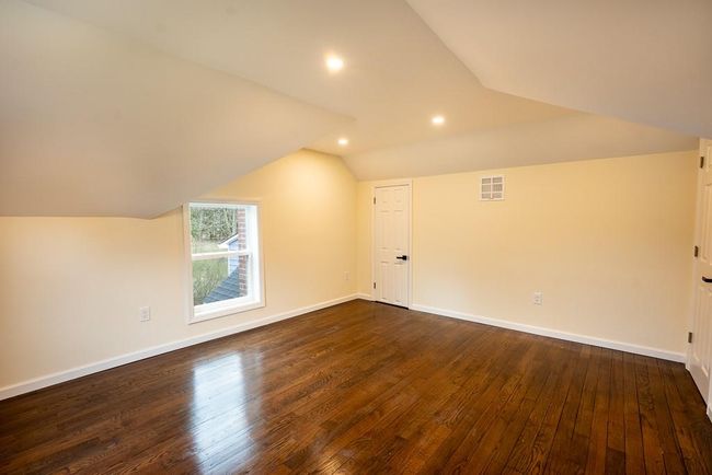 Master bedroom on second floor featuring dark wood finished floors, visible vents, baseboards, and lofted ceiling | Image 24