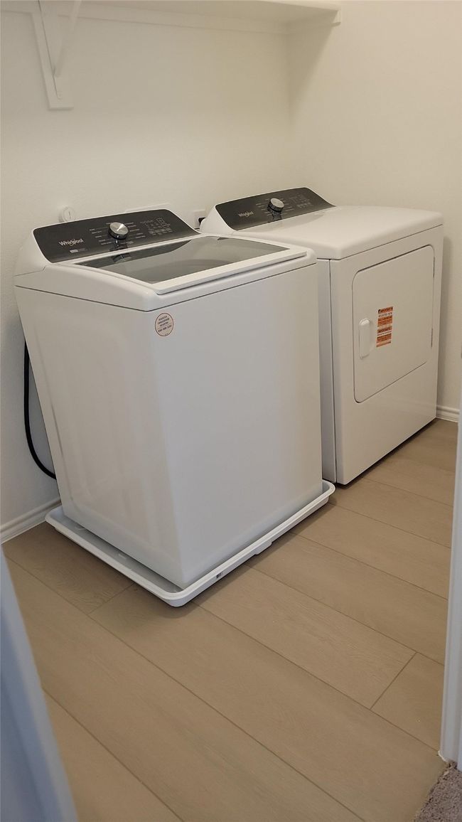 Clothes washing area with washing machine and clothes dryer, light wood-style flooring, laundry area, and baseboards | Image 6