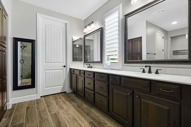 Full bathroom with double vanity, wood tiled floors, a shower, and baseboards | Image 27