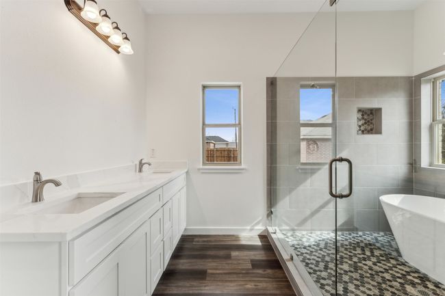 Bathroom featuring a soaking tub, healthy amount of natural light, double vanity, and wood finished floors | Image 31