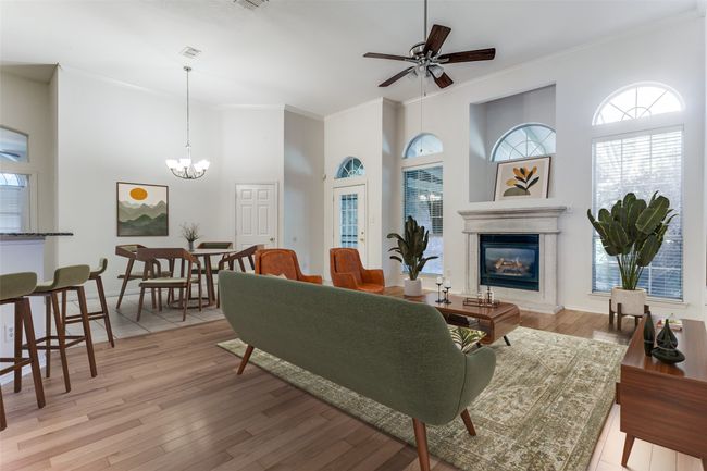 Living room featuring crown molding, a ceiling fan, plenty of natural light, a towering ceiling, and a glass covered fireplace | Image 10